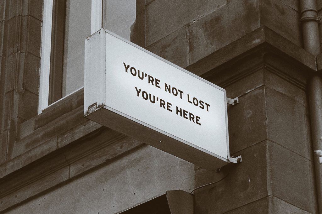 A white sign saying you are not lost, you are here on a brick building